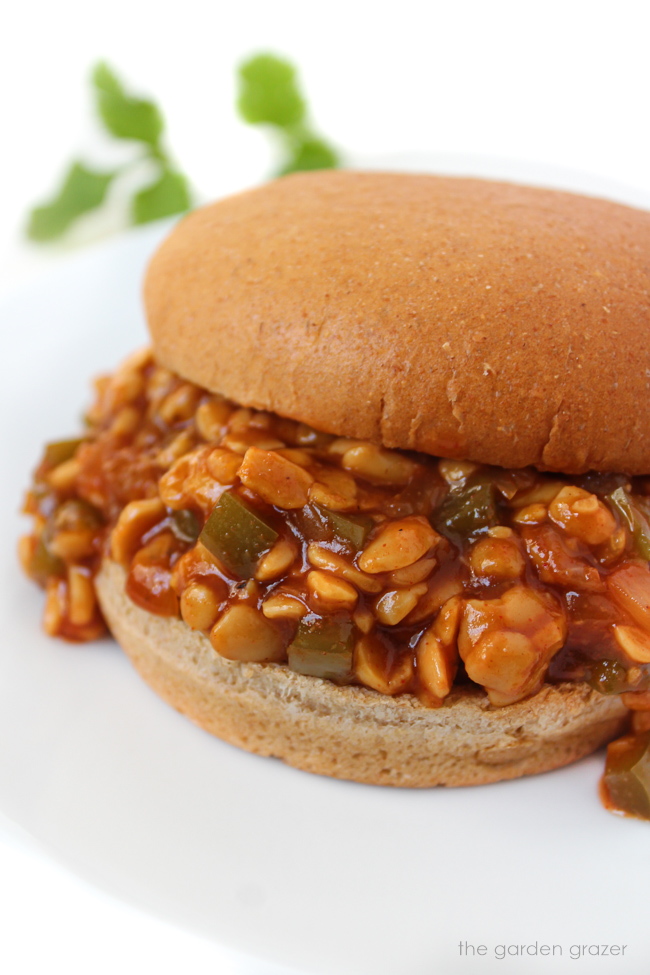 Vegan BBQ Tempeh Sloppy Joes in a wheat bun on a white plate