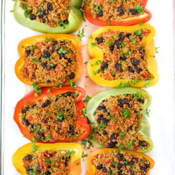 Stuffed bell peppers with couscous, black beans, and tomatoes in a large glass pan