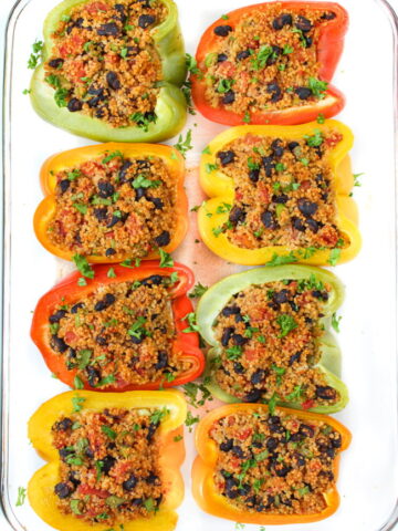 Stuffed bell peppers with couscous, black beans, and tomatoes in a large glass pan