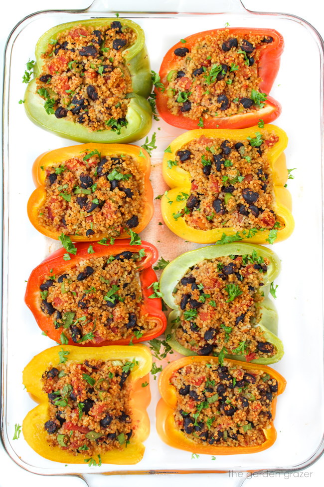 Stuffed bell peppers with couscous, black beans, and tomatoes in a large glass pan