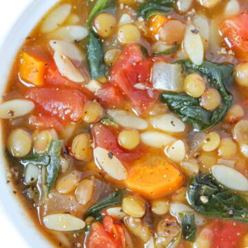 Bowl of vegan lentil orzo soup with spinach