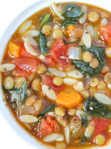 Bowl of vegan lentil orzo soup with spinach