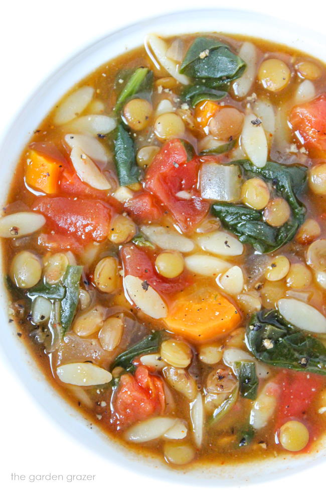 Bowl of vegan lentil orzo soup with spinach