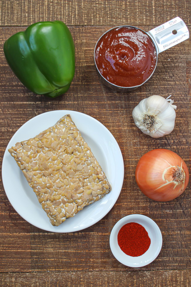 Tempeh, green bell pepper, onion, and garlic ingredients on a wooden table