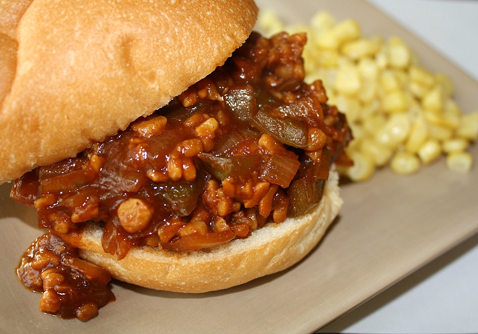 Vegan tempeh sloppy joes on a bun with a side of corn
