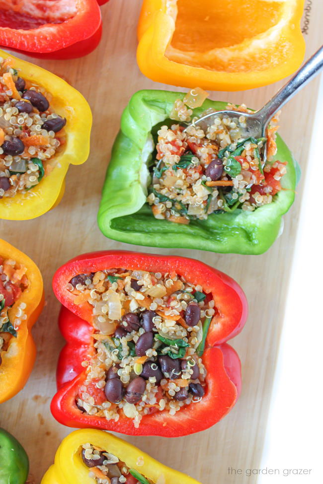 Spoon filling bell pepper halves with quinoa and spinach mixture