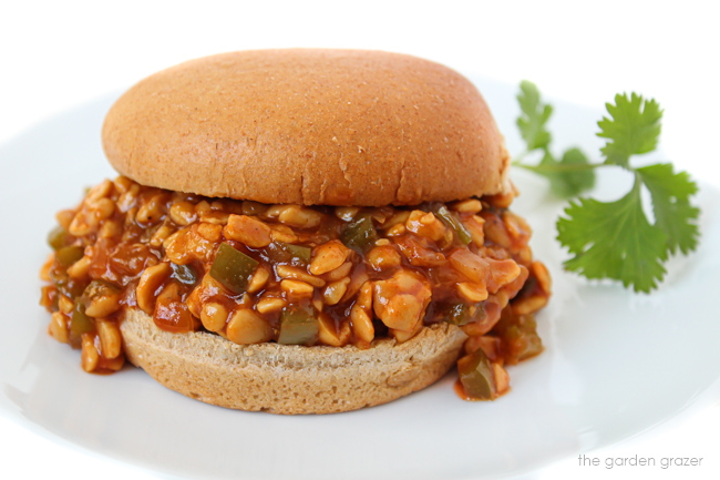 Sloppy joe sandwich on a white plate with cilantro garnish