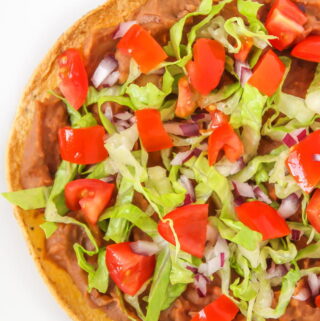 Vegan bean tostada with lettuce, tomato, and onion