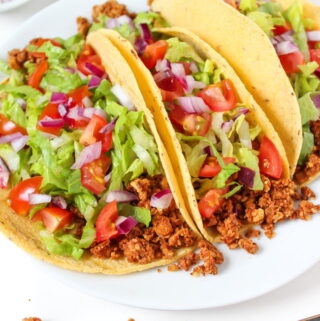 Plate of three vegan tacos with chickpea-walnut taco filling