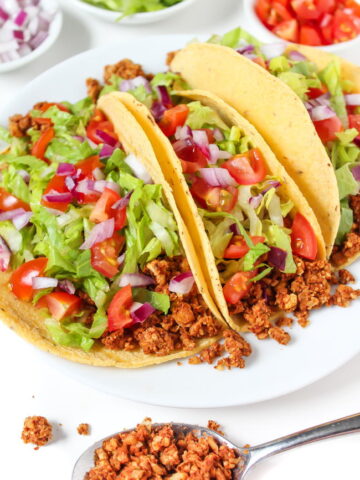 Plate of three vegan tacos with chickpea-walnut taco filling