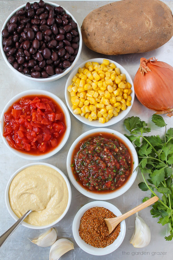 Black beans, sweet corn, onion, garlic, salsa, tomatoes, and taco seasoning ingredients laid out on a metal tray
