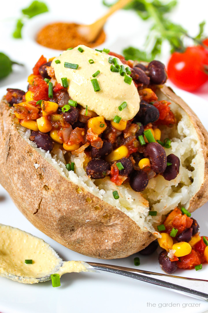 Close-up view of a Mexican Baked Potato topped with cashew queso and fresh chives