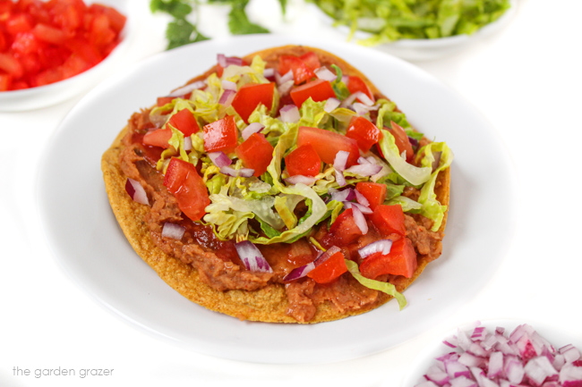 Vegan Refried Bean Tostadas on a white plate topped with lettuce and tomato