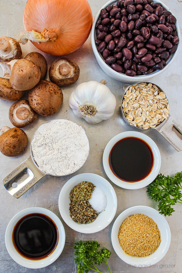 Beans, onion, garlic, oat flour, oats, flax, parsley, and spice ingredients laid out on a metal tray