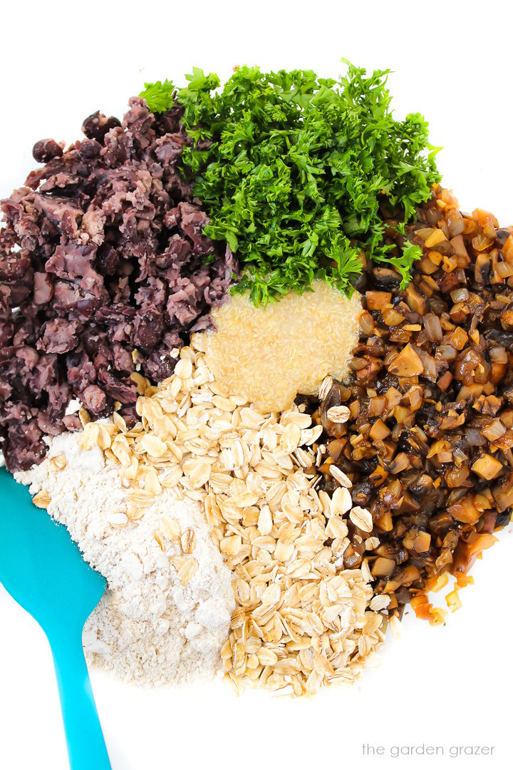 Combining burger mixture ingredients together in a large glass bowl with spatula