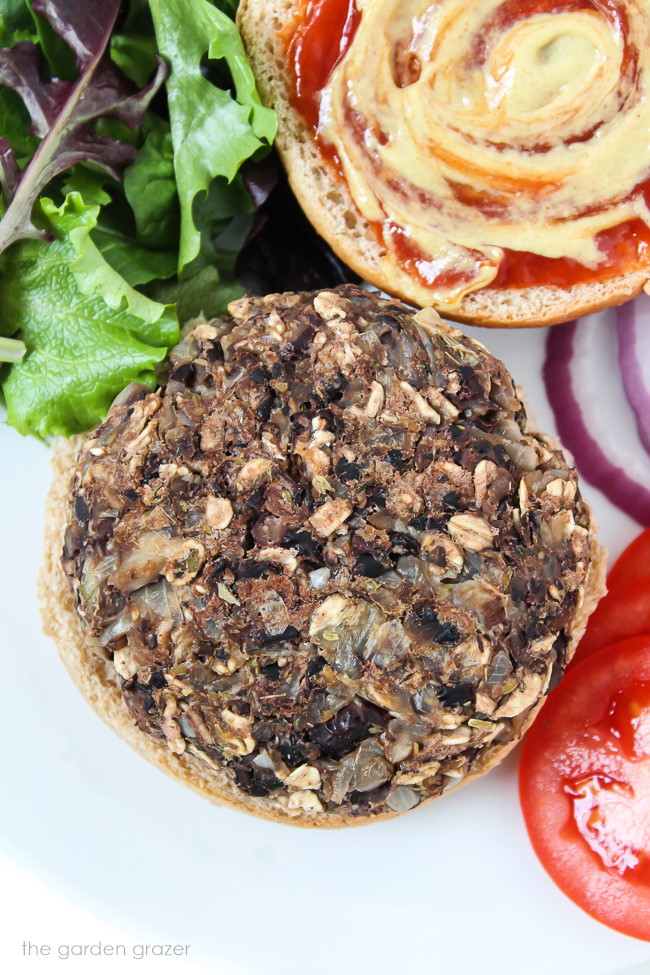 Open-faced mushroom burger on a white plate with toppings on the side