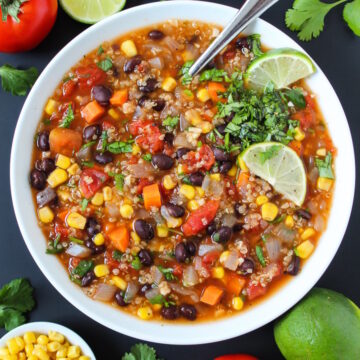Black bean and quinoa soup with sweet corn in a white bowl with serving spoon