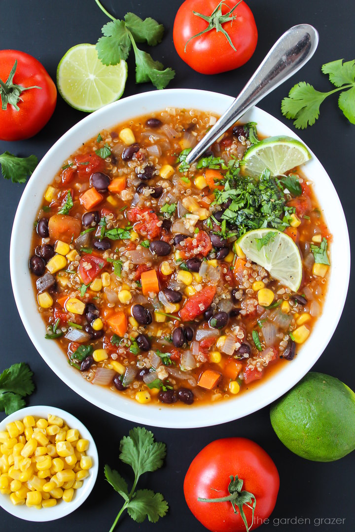 Black bean and quinoa soup with sweet corn in a white bowl with serving spoon