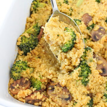 Vegan cheesy broccoli quinoa casserole with mushrooms in a large white baking dish