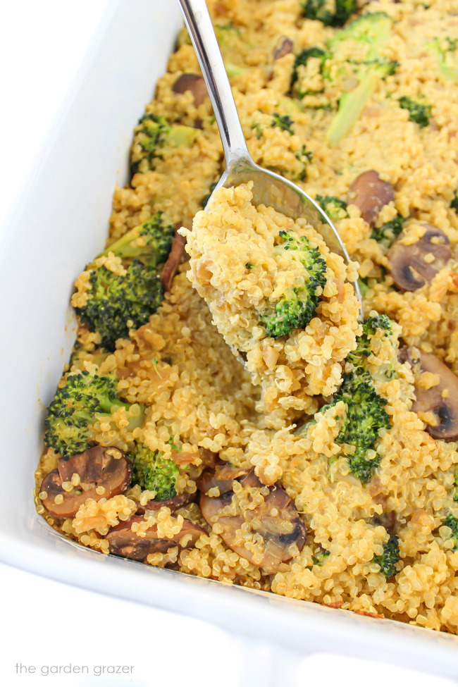 Vegan cheesy broccoli quinoa casserole with mushrooms in a large white baking dish