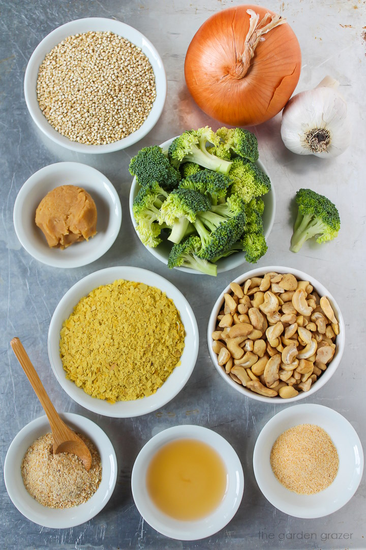 Onion, garlic, white miso, cashews, nutritional yeast, vinegar, and seasoning ingredients laid out on a metal tray
