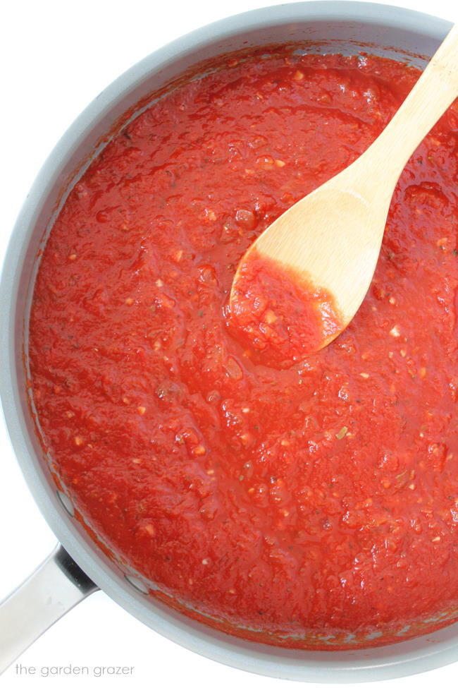 Homemade marinara sauce in a pan with wooden spoon