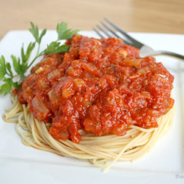 Spaghetti on a white plate topped with oil-free marinara sauce