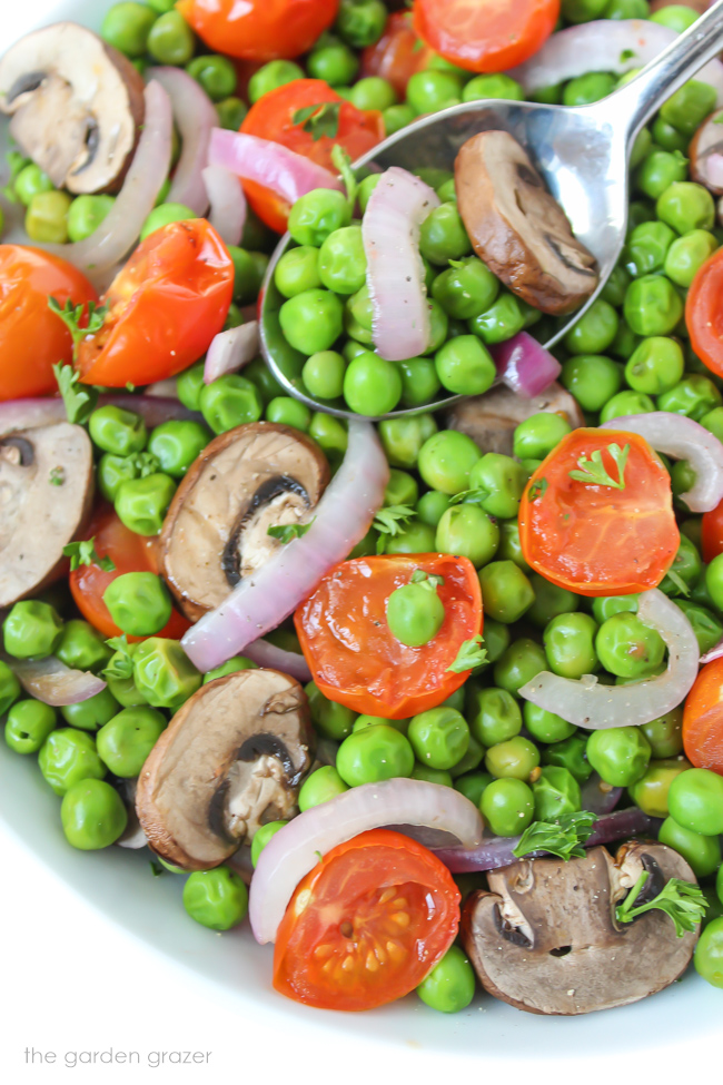 Vegan roasted peas and tomato in a bowl with spoon