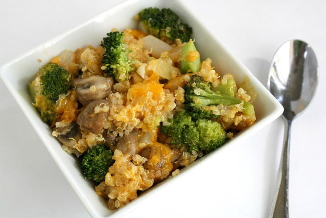 Vegan cheesy quinoa casserole in a small white bowl with spoon