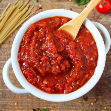 Vegan marinara sauce in a white bowl on a wooden table