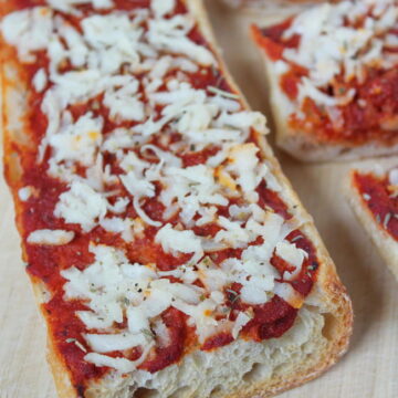 Vegan French bread cheese pizza on a cutting board