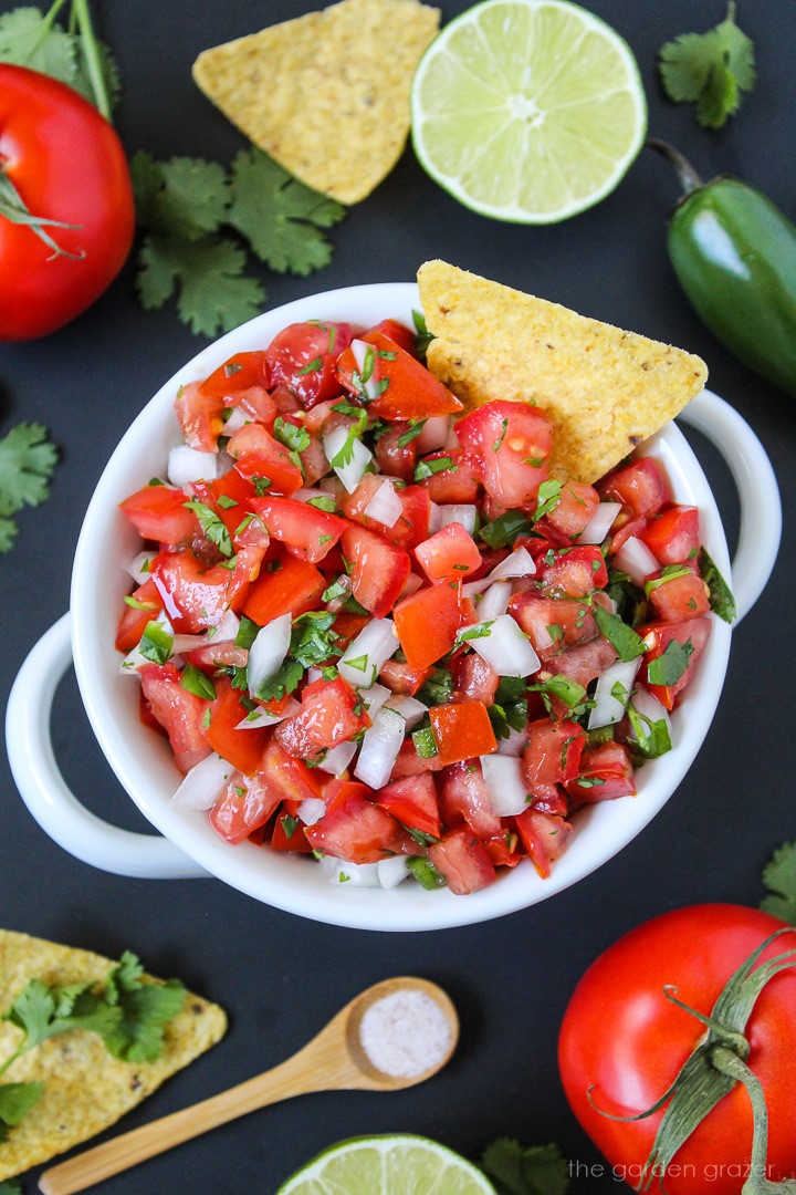 Salsa fresca in a white serving bowl with tortilla chip for dipping