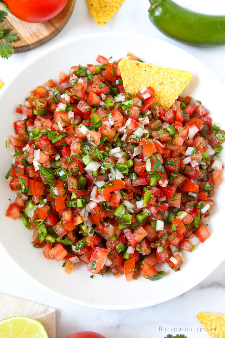 Overhead view of salsa fresca in a white serving bowl with tortilla chip