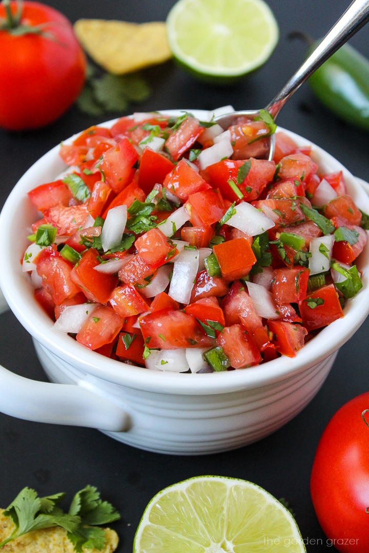 Fresh salsa fresca in a white bowl with serving spoon