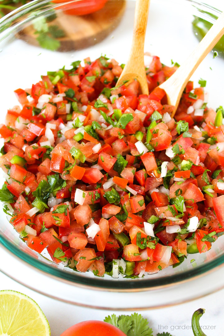 Fresh salsa fresca (Pico de Gallo) tossed together in a glass mixing bowl