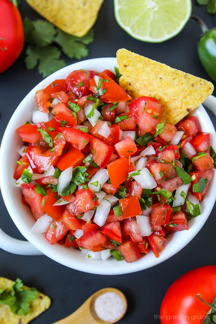 Close up view of fresh pico de gallo (salsa fresca) in a white bowl with tortilla chip