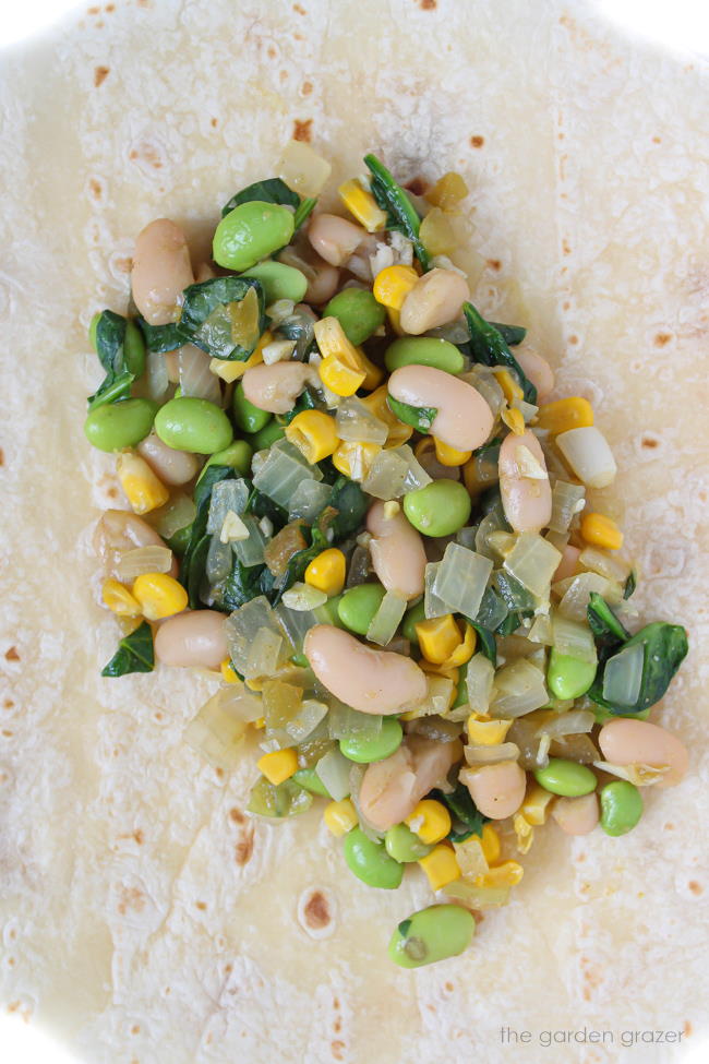 Open tortilla with filling of white beans and corn on top