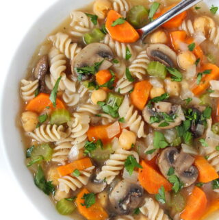 Bowl of vegan chickpea noodle soup topped with fresh parsley