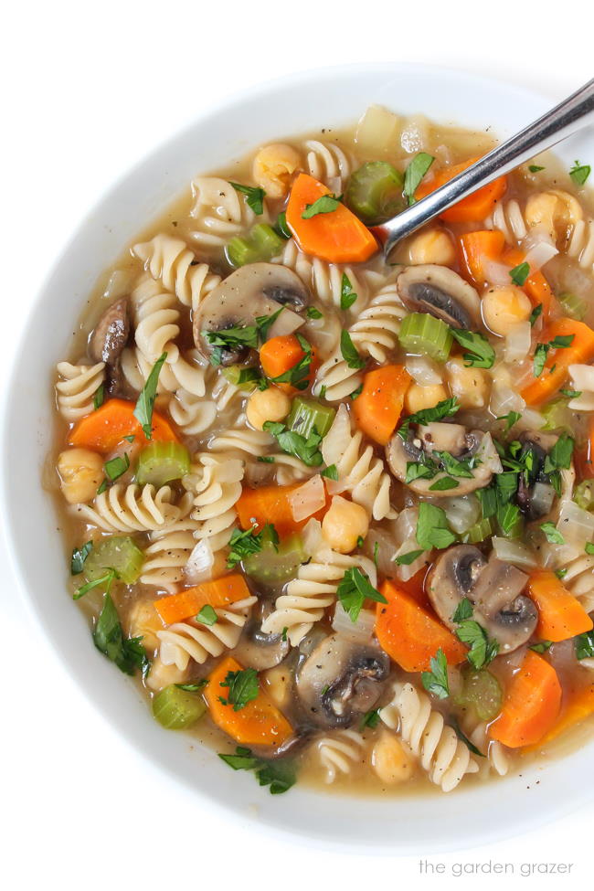 Bowl of vegan chickpea noodle soup topped with fresh parsley