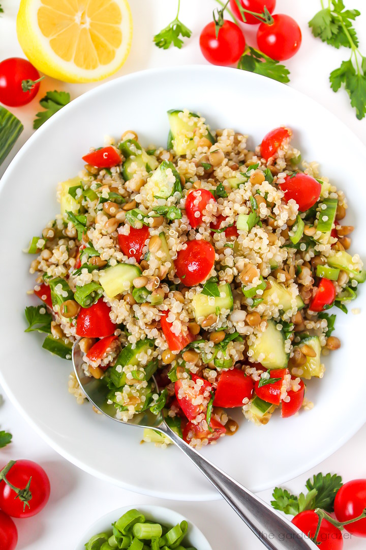 Overhead view of lentil quinoa salad in a white serving bowl with spoon