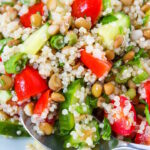 Close up view of lentil quinoa salad on a white plate with serving spoon