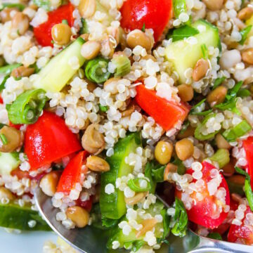 Close up view of lentil quinoa salad on a white plate with serving spoon