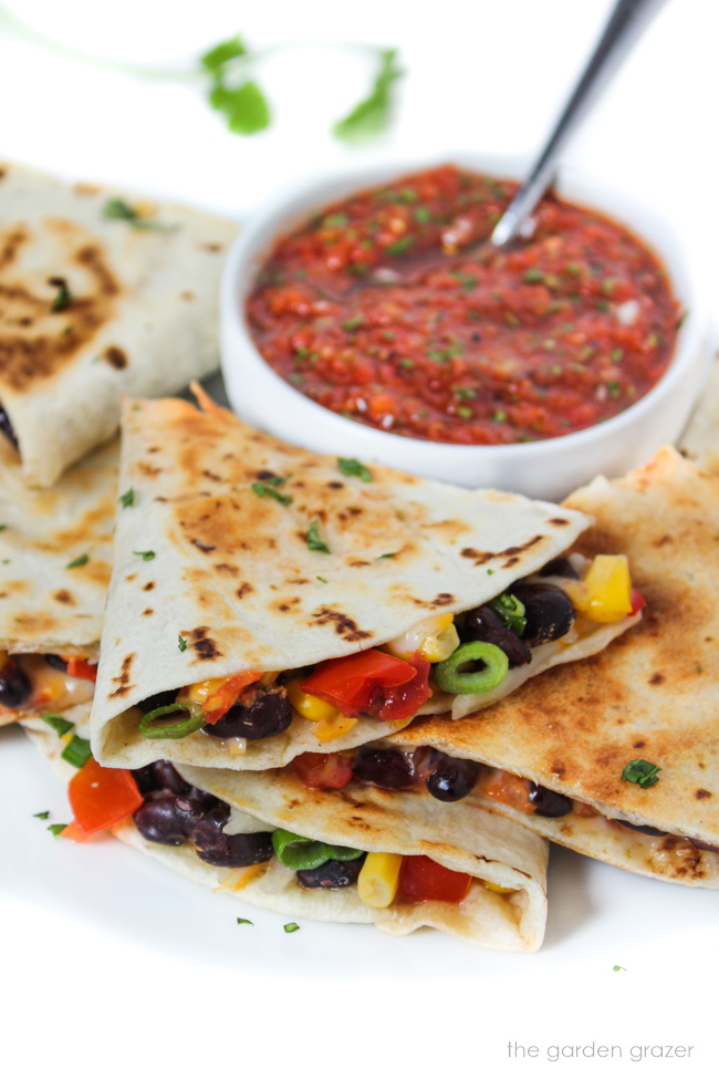 Vegan black bean corn quesadilla on a white plate with bowl of salsa