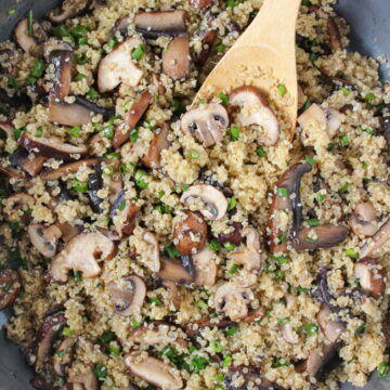 Asian-style quinoa with mushrooms cooking in a pan with wooden spoon