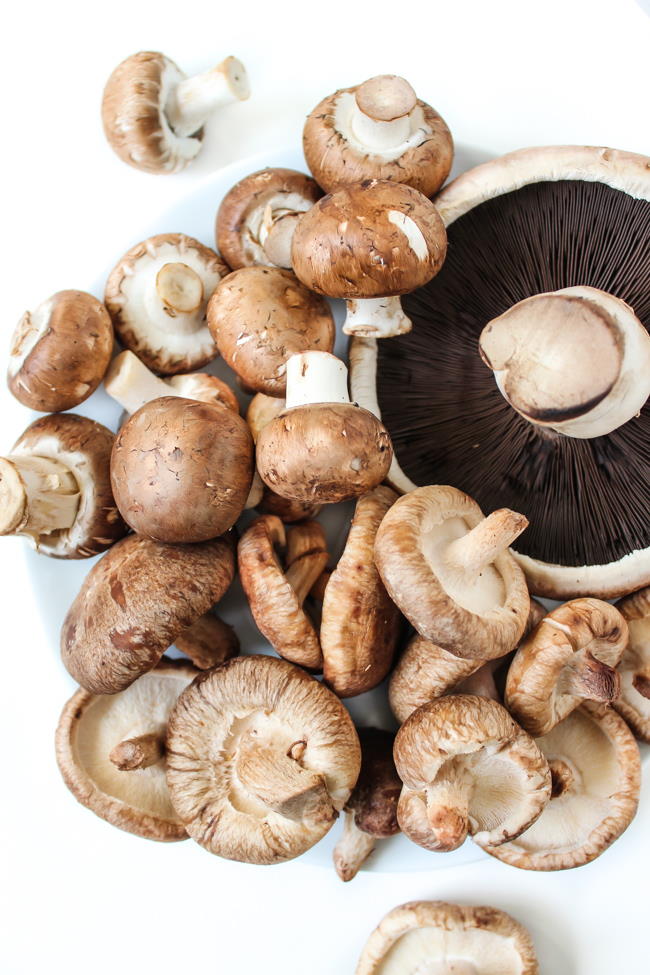 Shiitake, portobello, and cremini mushroom ingredients on a white table