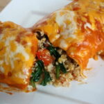 Vegan vegetable quinoa enchilada cut open on a white plate