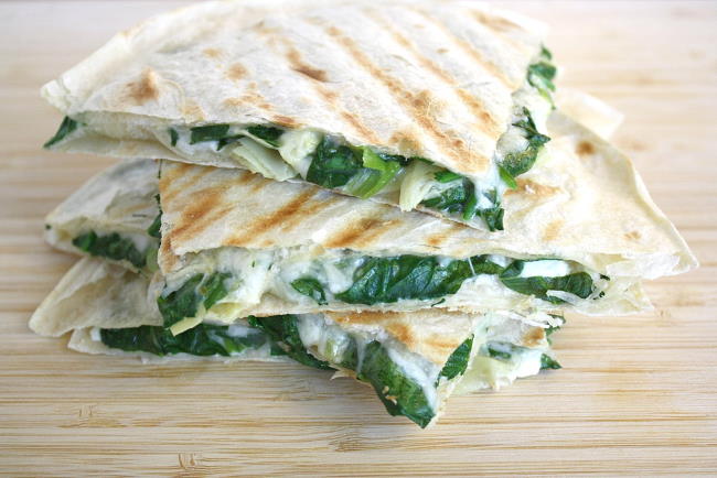 Cooked spinach artichoke quesadillas stacked on top of one another