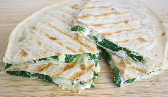 Vegan spinach quesadillas cut in half on a cutting board