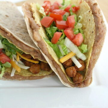 Two double decker chickpea tacos on a white plate