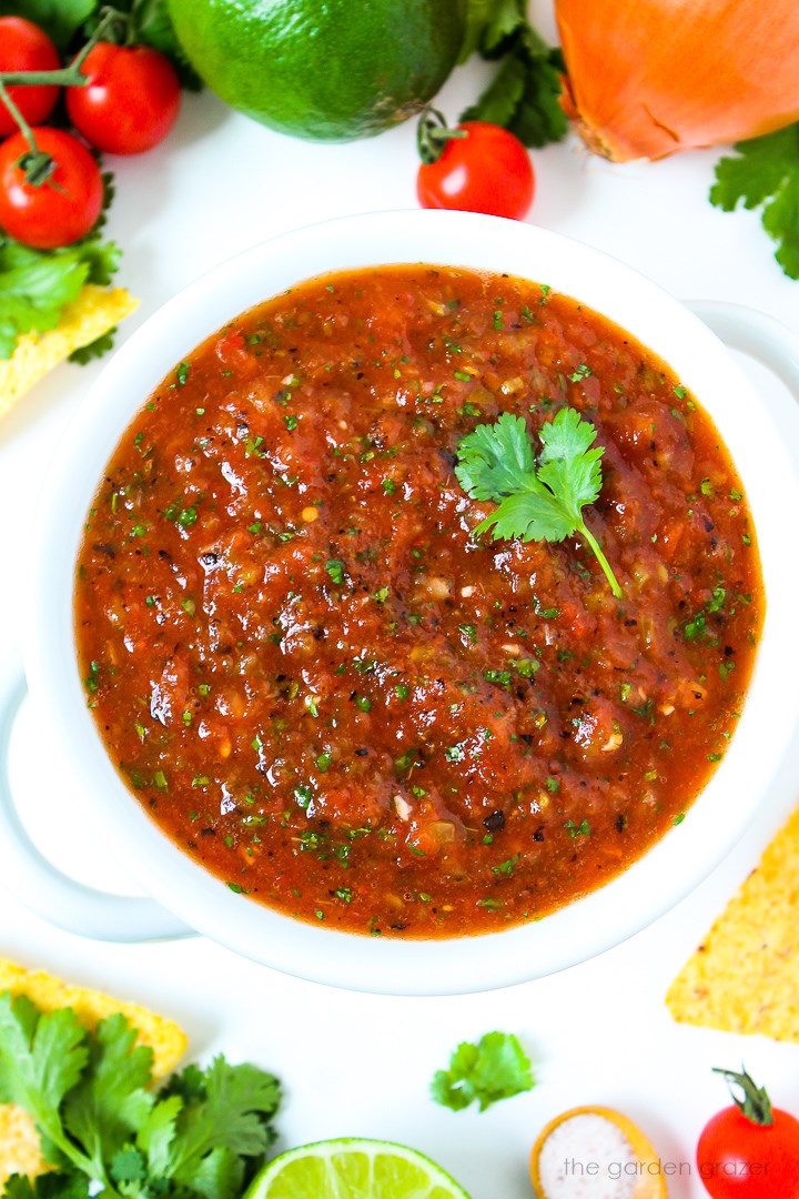 Overhead view of restaurant style blender salsa in a white bowl with cilantro garnish